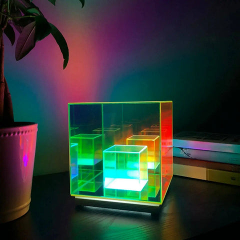 A Tesseract Hologram Designer Lamp illuminating a desk with its vibrant, multicolored LED lights, creating a mesmerizing and modern ambiance in the room.